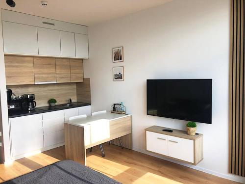 een woonkamer met een flatscreen-tv en een keuken bij Apartimento Hydral Aria in Wrocław