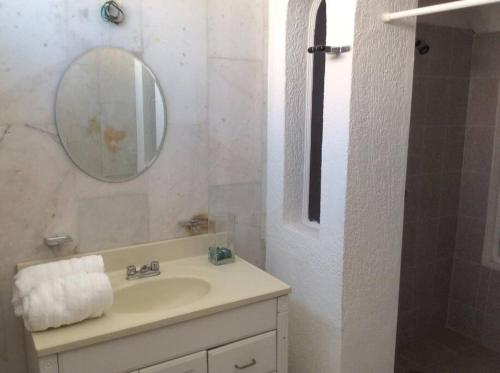 Baño blanco con lavabo y espejo en Hermoso Estudio Ubicado en el Cor de Cancún, en Cancún