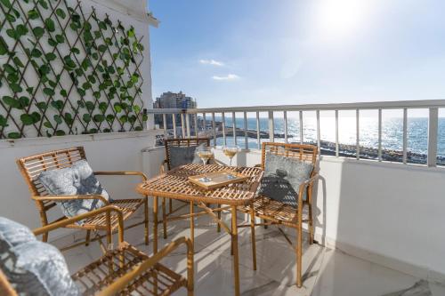 balcón con mesa, sillas y vistas al océano en Lovely Seaview Condo in Saba Pasha en Alexandria