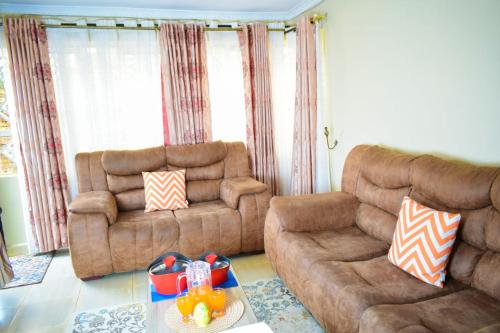 a living room with two couches and a table at Cozy 2 bedroom in a family home in Nakuru