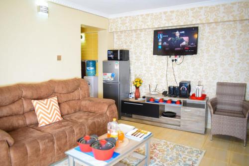 a living room with a couch and a tv at Cozy 2 bedroom in a family home in Nakuru