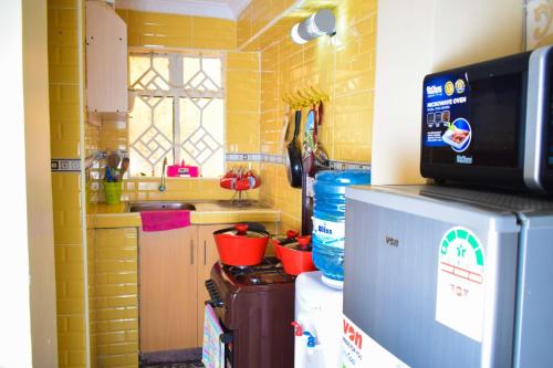 eine kleine Küche mit Spüle und Kühlschrank in der Unterkunft Cozy 2 bedroom in a family home in Nakuru