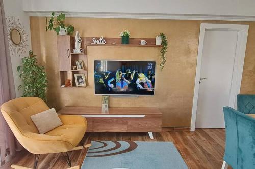 een woonkamer met een televisie en een stoel bij Apartment Adrian in Kaštela