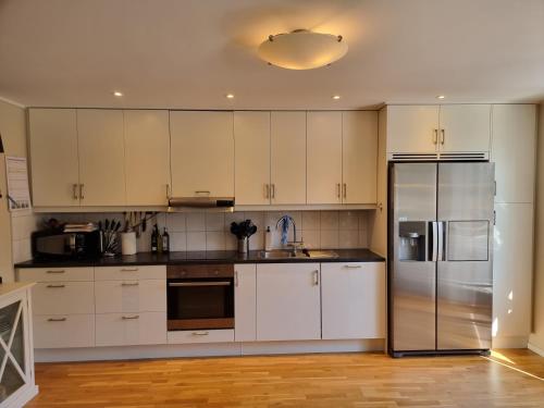 a kitchen with white cabinets and a stainless steel refrigerator at Trevlig lägenhet nära Strömstad centrum in Strömstad