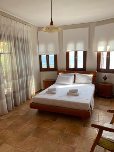 a bedroom with a bed with white sheets and windows at La Grande Maison,Lefokastro in Afissos