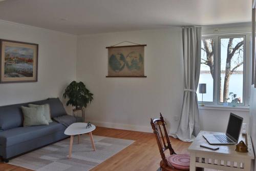 a living room with a couch and a table with a laptop at Captivating Harbor View Suite in Östhammar