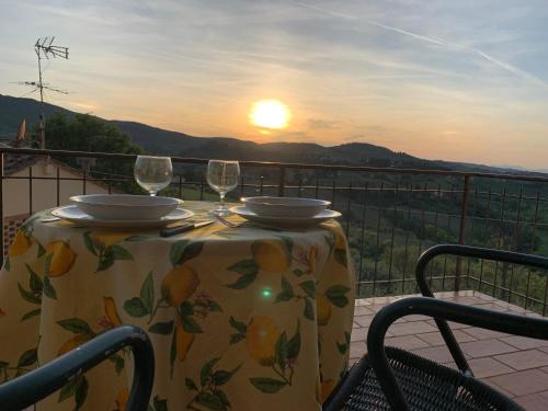 a table with two wine glasses on a balcony with the sunset at Appartamento Donella con parcheggio privato in San Gimignano