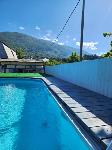a swimming pool with a fence and mountains in the background at Гостевой дом у Ларисы in Gagra