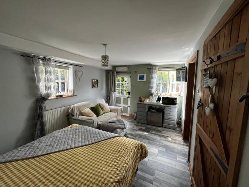 a bedroom with a bed and a couch and a kitchen at Pear Tree Cottage in Shrewsbury