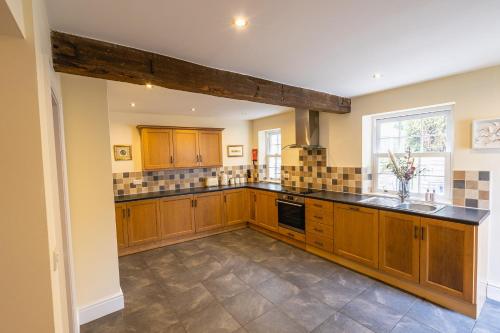une grande cuisine avec des placards en bois et une fenêtre dans l'établissement Entire cottage & private garden in Scorton, à Scorton