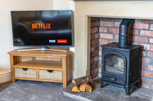 a fireplace with a television and a stove at Entire cottage & private garden in Scorton in Scorton