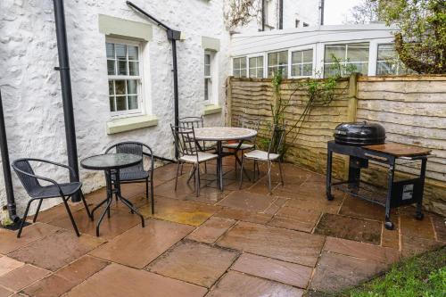 a patio with tables and chairs and a grill at Entire cottage & private garden in Scorton in Scorton
