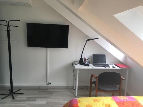 1 dormitorio con escritorio, ordenador portátil y TV en Agréable chambre indépendante chez Virginie&Henri, en Le Mée-sur-Seine