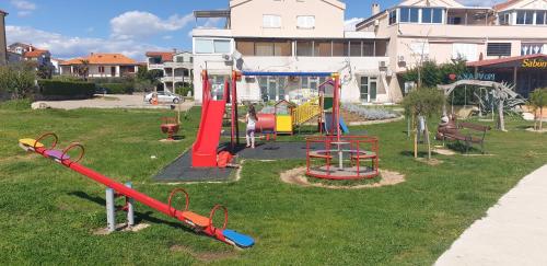 a park with a playground with slides and swings at Mobile home Lana Dalmacija kamp Privlaka in Privlaka