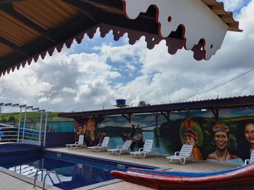 una piscina en un parque temático con sillas y un mural en Hotel La Villa Morena, en Oiapoque