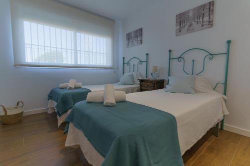 2 łóżka w pokoju z niebieskimi ścianami i oknami w obiekcie Casa Bluebelle Guadalmina w Marbelli