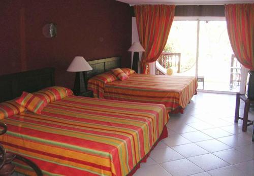 2 Betten in einem Hotelzimmer mit roten Vorhängen in der Unterkunft Tropical Manor Inn - Kingston in Kingston