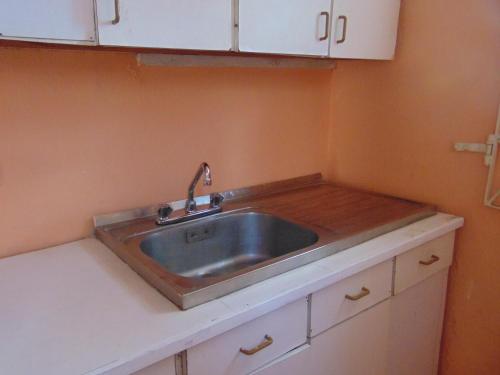 a kitchen counter with a sink and white cabinets at Tropical Manor Inn - Kingston in Kingston