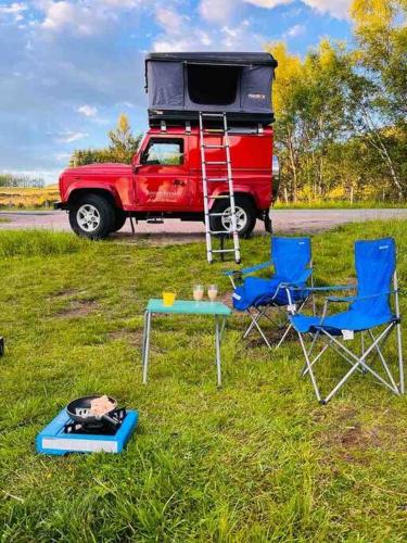 a red truck with a camper and two chairs and a table at Bonniebreaks in Avoch