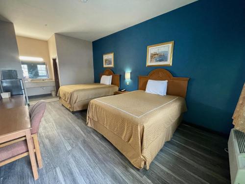 a hotel room with two beds and a blue wall at Airport inn & suites in Corpus Christi