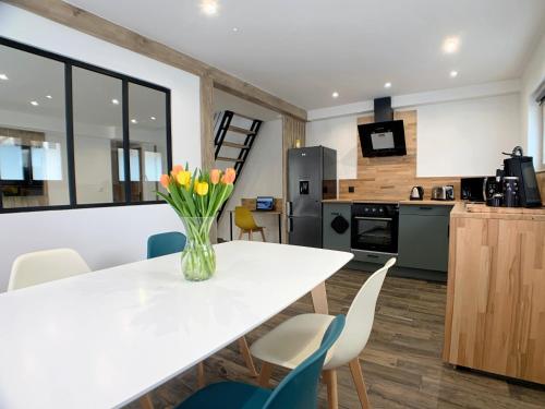 une cuisine avec une table blanche et des fleurs jaunes dans un vase dans l'établissement Eco-Appart'hôtel Rouen / SLT, à Rouen