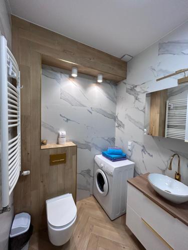 a bathroom with a toilet and a sink and a washing machine at Apartament Pileckiego in Suwałki