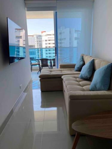 a living room with a couch and a view of a building at Reserva del Mar - Apto con vista al mar in Santa Marta