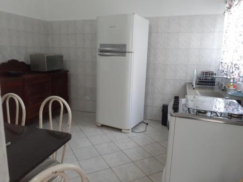 una cucina con frigorifero, tavolo e sedie di Casa Agradável próxima ao Bosque a Porto Feliz