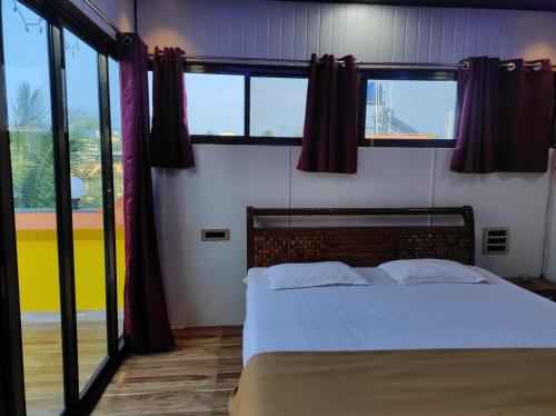 a bedroom with a bed and some windows at Diamond Cottage in Alibaug