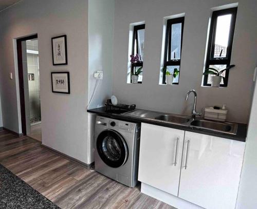 a kitchen with a washing machine and a sink at Waterkloof Nature Reserve Studio Apartment in Pretoria