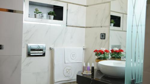 a bathroom with a sink and red flowers on a counter at Hotel Riad Taounate in Taounate