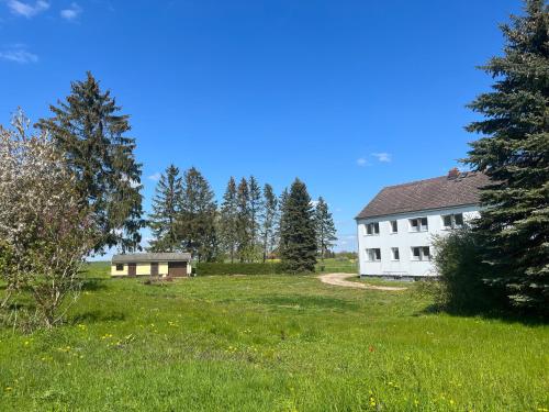 a white house in a field with trees at Monteur-Pension N2 in Siemitz