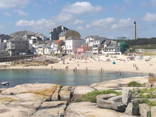 un grupo de personas en una playa con edificios en EnSAN CIPRIÁN Faro de Punta Atalaya, en Cervo