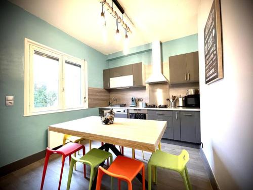 une cuisine avec une table en bois et quatre chaises colorées dans l'établissement Maison Gabriel - charmant lieu de vie pour 8 pers., à Berck-sur-Mer