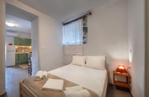 a white bedroom with a bed and a kitchen at Feneri 3 -Cozy rustic Apt 20' from Elafonisi beach in Perivólia