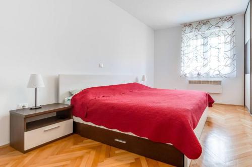 um quarto com uma cama com um cobertor vermelho em NEW apartmant for 5 em Solin