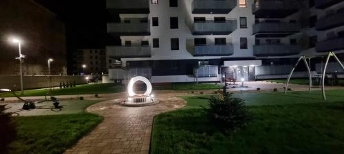 a building at night with a sculpture in front of it at 62m2 Apartament PREMIUM Łąki i Pola, ELEKTRYCZNE ROLETY, KLIMATYZACJA, GARAŻ, ŁADOWARKA AUT ELEKTRYCZNYCH in Suwałki