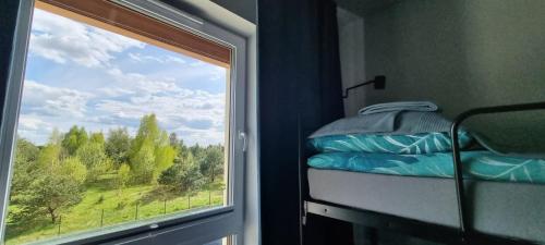 a room with a window with a bed and a view at 62m2 Apartament PREMIUM Łąki i Pola, ELEKTRYCZNE ROLETY, KLIMATYZACJA, GARAŻ, ŁADOWARKA AUT ELEKTRYCZNYCH in Suwałki