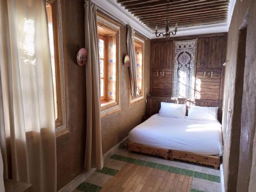 a small bedroom with a bed and two windows at RIAD LA SANTA in Chefchaouen