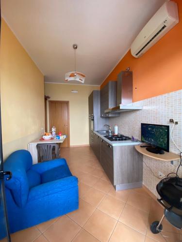 a living room with a blue couch and a kitchen at Appartamento con terrazzo sul mare. in Capo Rizzuto