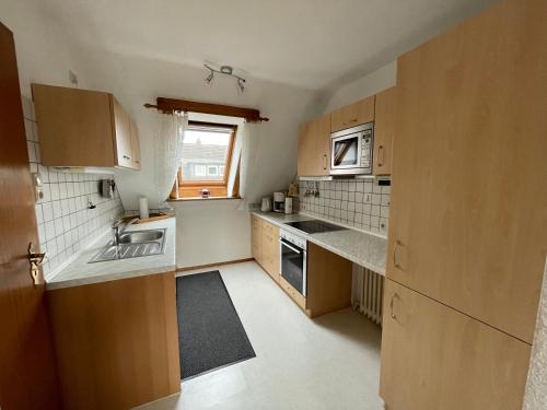 a small kitchen with wooden cabinets and a window at Haus Mariechen in Hooksiel