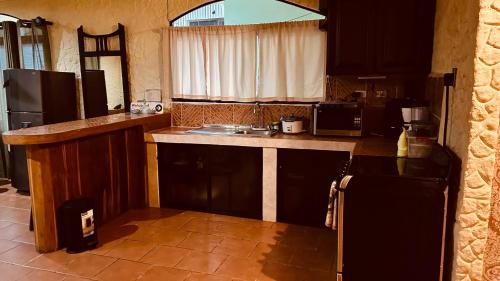 a kitchen with a counter and a sink and a refrigerator at Casa Encantada offers you Two-Bedroom House, 1 Tiny Apartment & 3 Double Rooms in Manuel Antonio