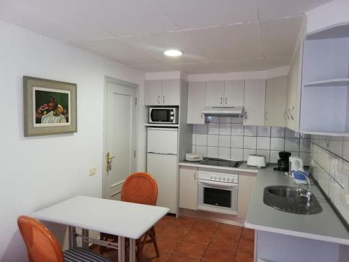 - une cuisine avec des appareils blancs, une table et des chaises dans l'établissement apartamento CASA TELA, à Tazacorte