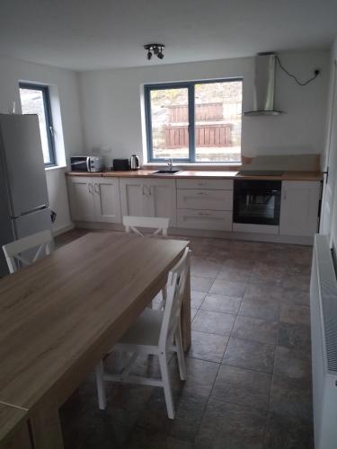 a kitchen with a wooden table and a refrigerator at Cornacarta Holiday House in Boyle