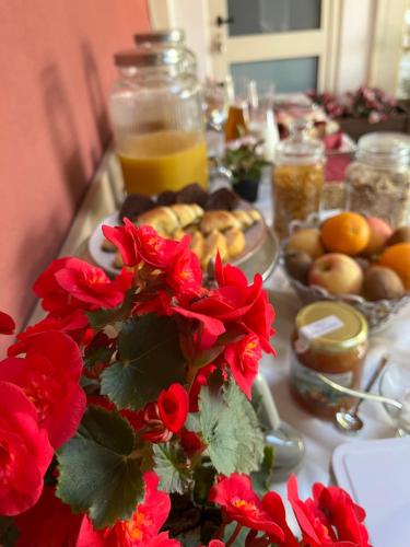 a table with red flowers and a plate of food at Bed & Breakfast La Rondinella in Cerasolo
