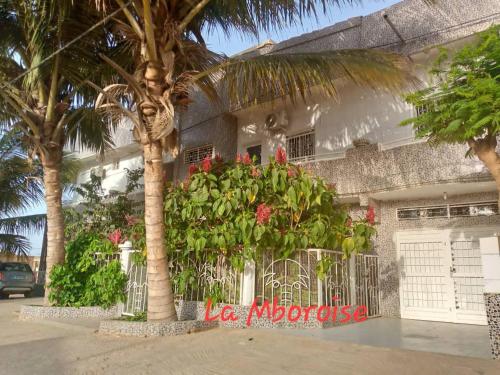 a building with palm trees and flowers in front of it at La Mboroise in Mboro