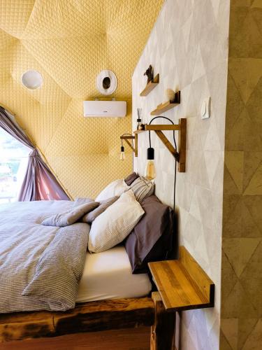 a bed in a room with a yellow wall at Nomad Glamping in Šipovo