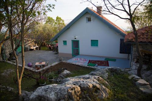 a white house with a yard with a rock at Vila Agroturizam Kućica Mostar-Welcome bikers in Mostar