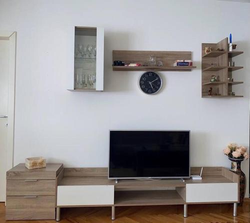 uma sala de estar com televisão e um relógio na parede em Rooftop terrace appartment em Skopje