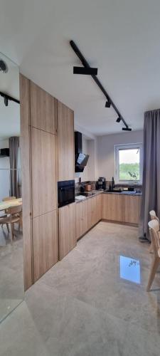 a large kitchen with wooden cabinets and a window at 62m2 Apartament PREMIUM Łąki i Pola, ELEKTRYCZNE ROLETY, KLIMATYZACJA, GARAŻ, ŁADOWARKA AUT ELEKTRYCZNYCH in Suwałki